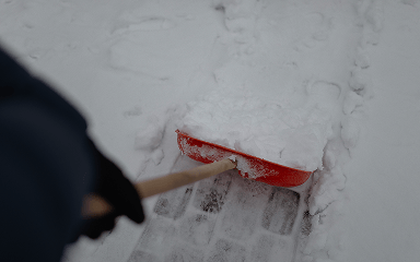 Schneeschieber beim Räumen eines verschneiten Weges